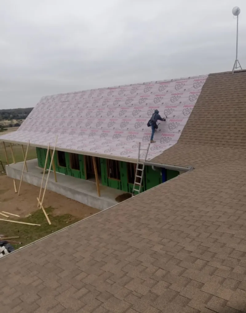 Worker preparing underlayment for a metal roof installation in Ashburn